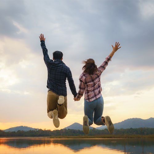 Happy Asian Couple Tourists Jumping Near Lake Vacations — Beenleigh, QLD — Christobel Counselling